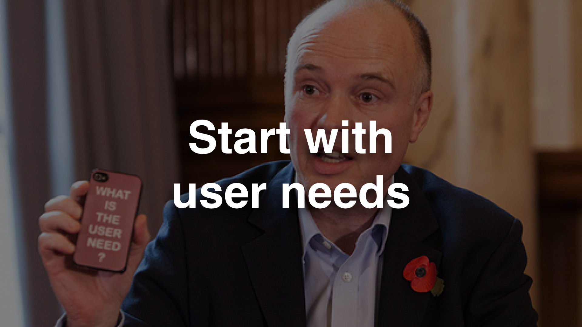 "Start with user needs" - photo of Liam Maxwell holding a mobile phone that says "what is the user need?"